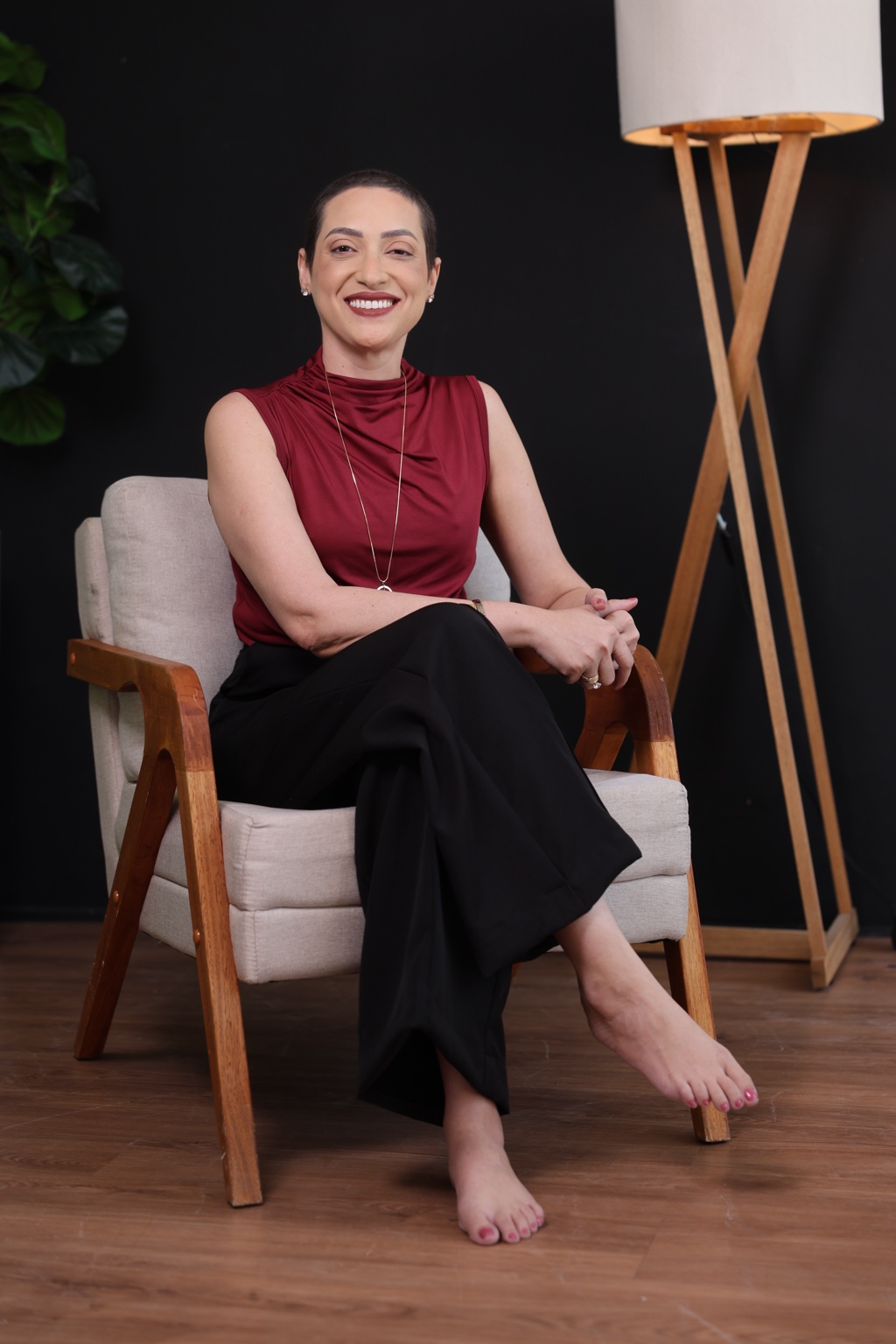 Patrícia Cronemberger sentada, vestindo blusa vinho